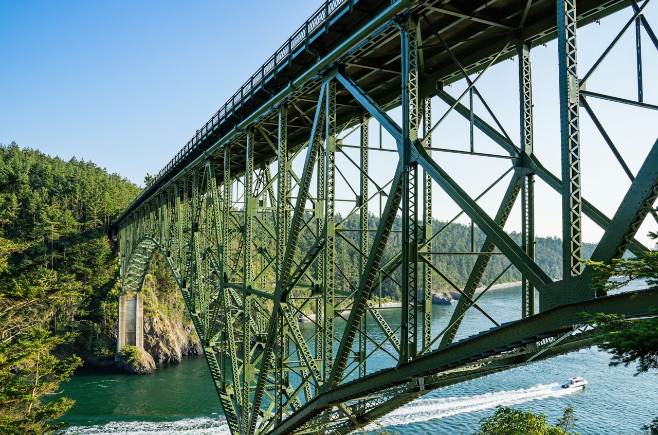 Steel bridge spanning a forested coastal channel